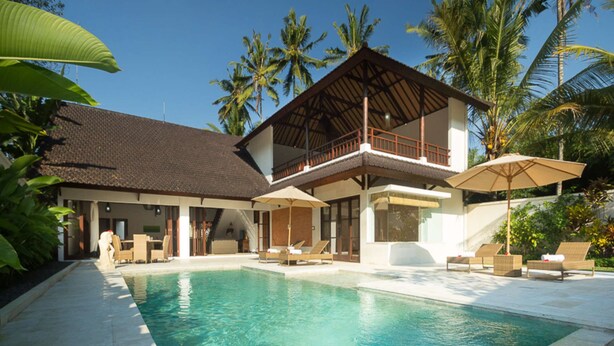 Un complexe hôtelier à deux étages doté d’une piscine, de chaises longues et de parasols.