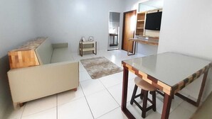 Un salon moderne avec un canapé, une table à manger au plateau en verre et une petite table d’appoint.