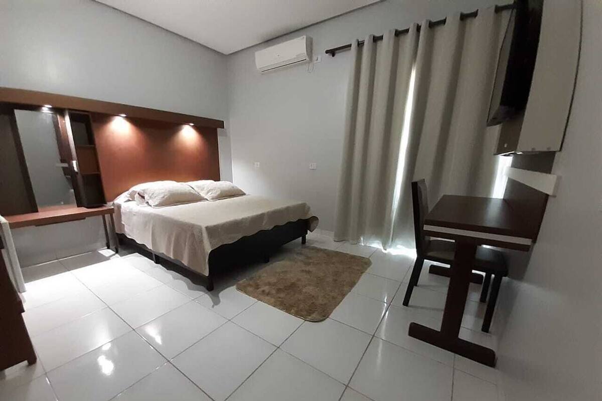 Una habitación de hotel moderna con cama, mesita de noche, escritorio y silla.