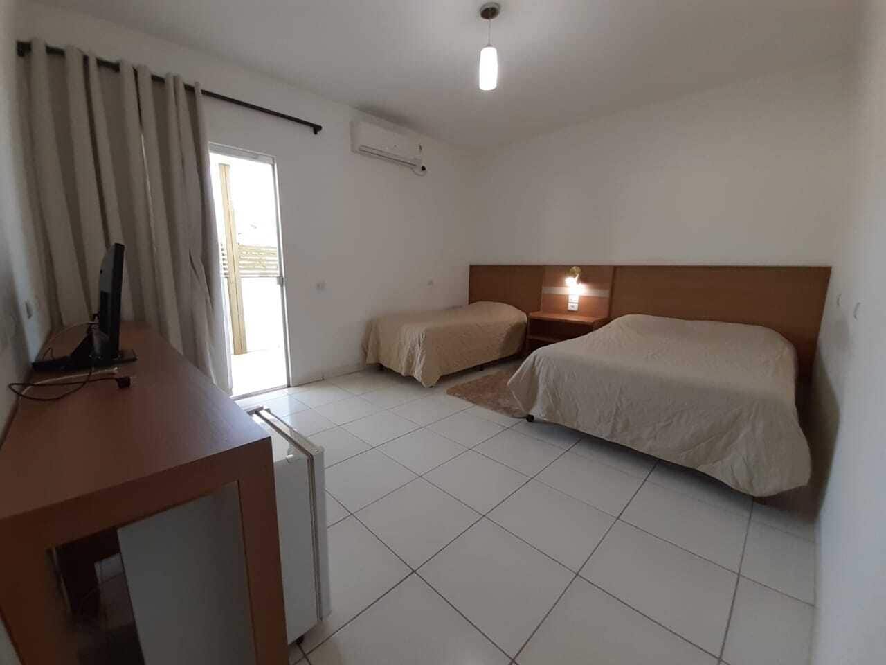 A hotel room with a bed, a desk, and a window with curtains.