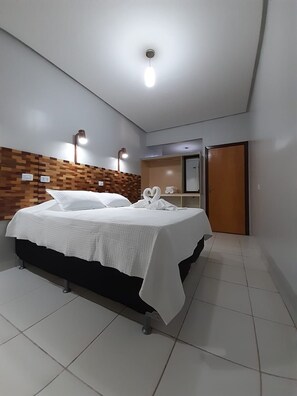A hotel room with a bed, a wooden headboard, a wardrobe, and a door. - Hotel Samambaia (Indiara)