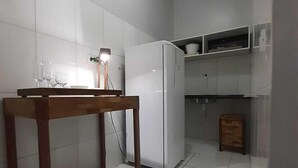Une cuisine avec des carreaux blancs, une table en bois et un réfrigérateur blanc.