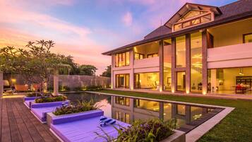 A modern house with a large pool, outdoor seating, and a well-maintained garden.