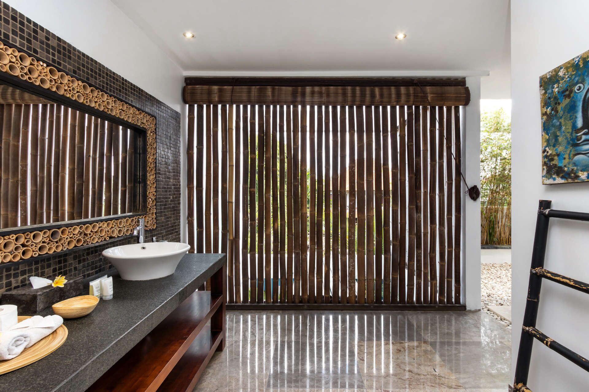 Um banheiro moderno com uma pia grande, paredes revestidas de azulejos escuros e um cortinado de bambu.