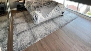 A modern bedroom with a large bed, two bedside tables, and a large window with a view.
