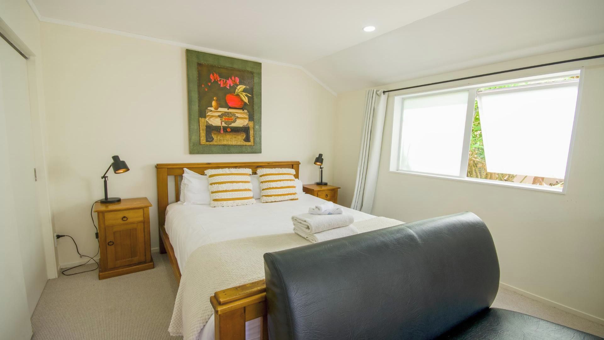 Une chambre d’hôtel avec un lit, des tables de chevet, une chaise, un tableau et une fenêtre.