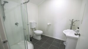 A bathroom with a glass-enclosed shower, a toilet, and a sink. - Beautiful & Bright Studio APT (Auckland)