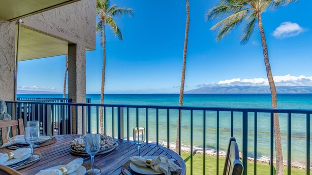 A table set for dining with a view of the ocean and palm trees. - Newly upgraded kitchen with oceanfront views (Lahaina)