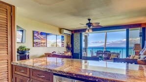 A kitchen with a large island, a dining area with a view, and a ceiling fan. - Newly upgraded kitchen with oceanfront views (Lahaina)