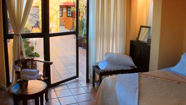 Une chambre d’hôtel avec un lit, une chaise, une petite table et une vue sur l’extérieur.