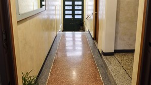 A hallway with a polished floor, a large mirror on the left, and a door at the end. - Comfortable apartment with garden view - Treviso center (Treviso)
