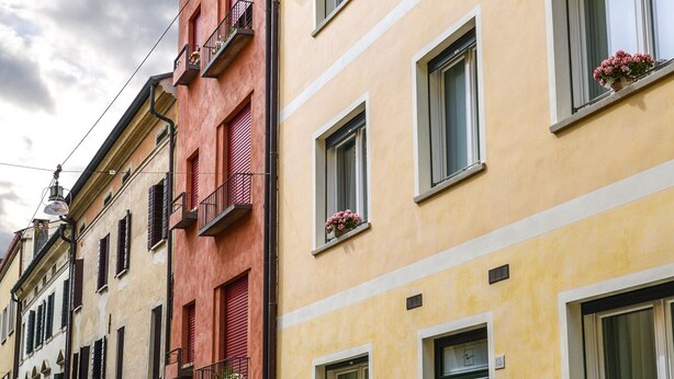 A row of colorful buildings with balconies and windows, a street in front, and a clear sky. - Comfortable apartment with garden view - Treviso center (Treviso)