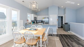 A modern kitchen with white cabinets, a stainless steel refrigerator, and a hanging light fixture.