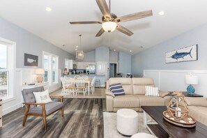 A spacious living area with a ceiling fan, a dining table with chairs, a sofa, and a coffee table.