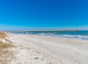 Ein Strand mit einer langen Pier, die sich ins Meer erstreckt.