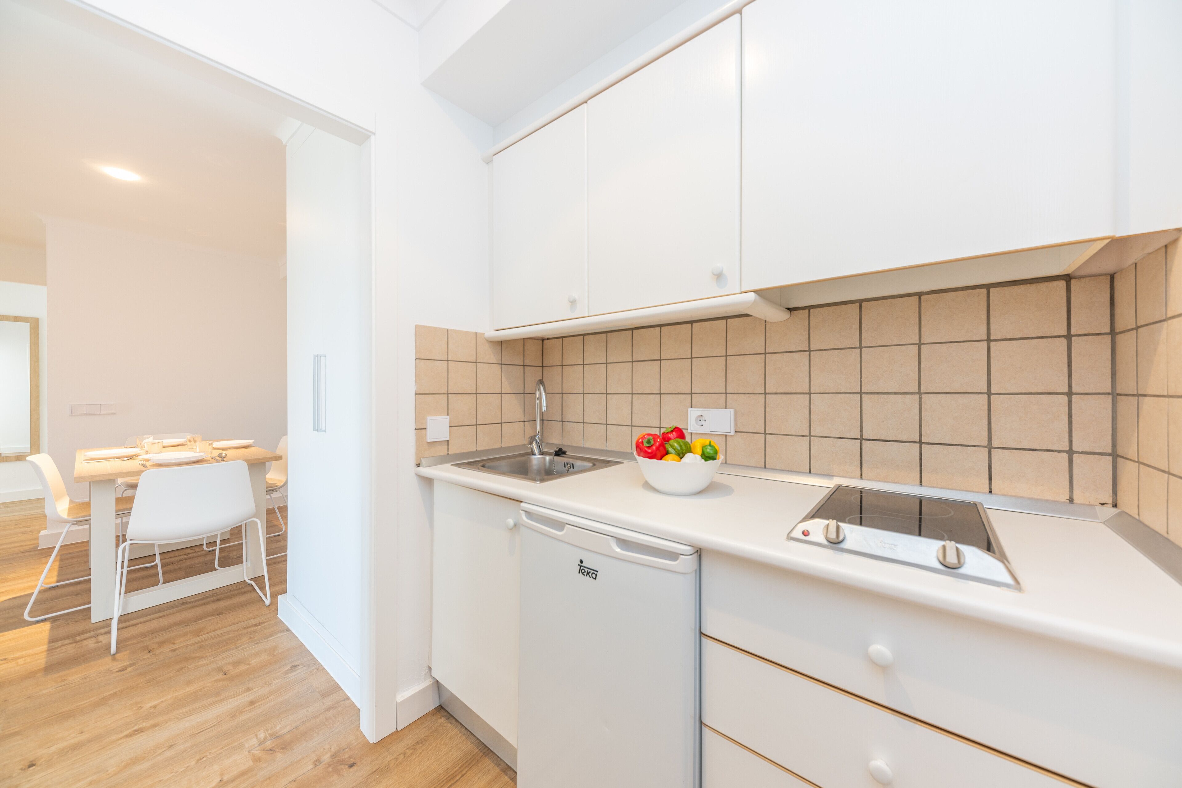 Una cocina moderna con armarios blancos, lavavajillas integrado y salpicadero de azulejos.