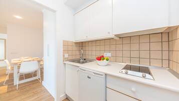 Una cocina moderna con armarios blancos, lavavajillas integrado y salpicadero de azulejos.