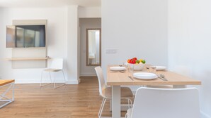 Zona pranzo moderna con tavolo in legno, sedie bianche e una ciotola di frutta.