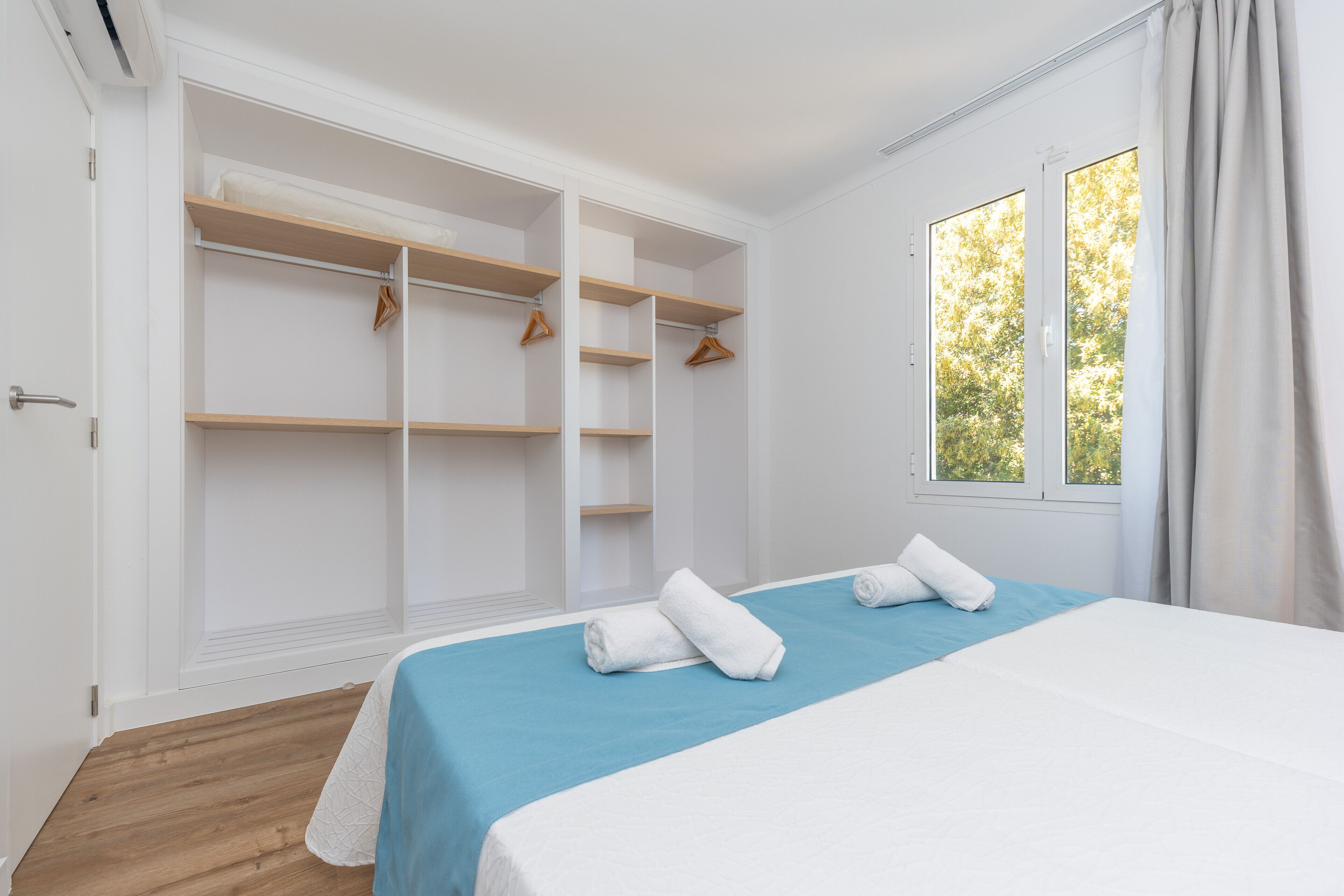 Une chambre à coucher avec un lit, une armoire et une fenêtre avec des rideaux.