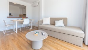 A modern living room with a sofa, a round coffee table, and a dining area with chairs and a table.