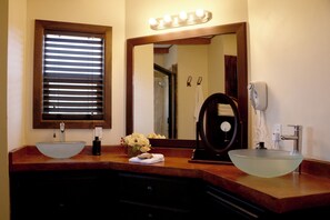 Une salle de bain avec deux lavabos, un miroir et une fenêtre avec des stores.