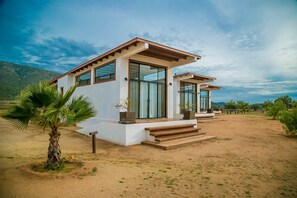 Une maison moderne à deux étages, dotée de grandes fenêtres et d’un porche en bois.
