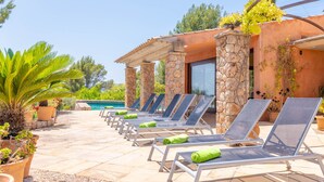 Un espace aménagé au bord de la piscine, avec des chaises longues et un mur en pierre.
