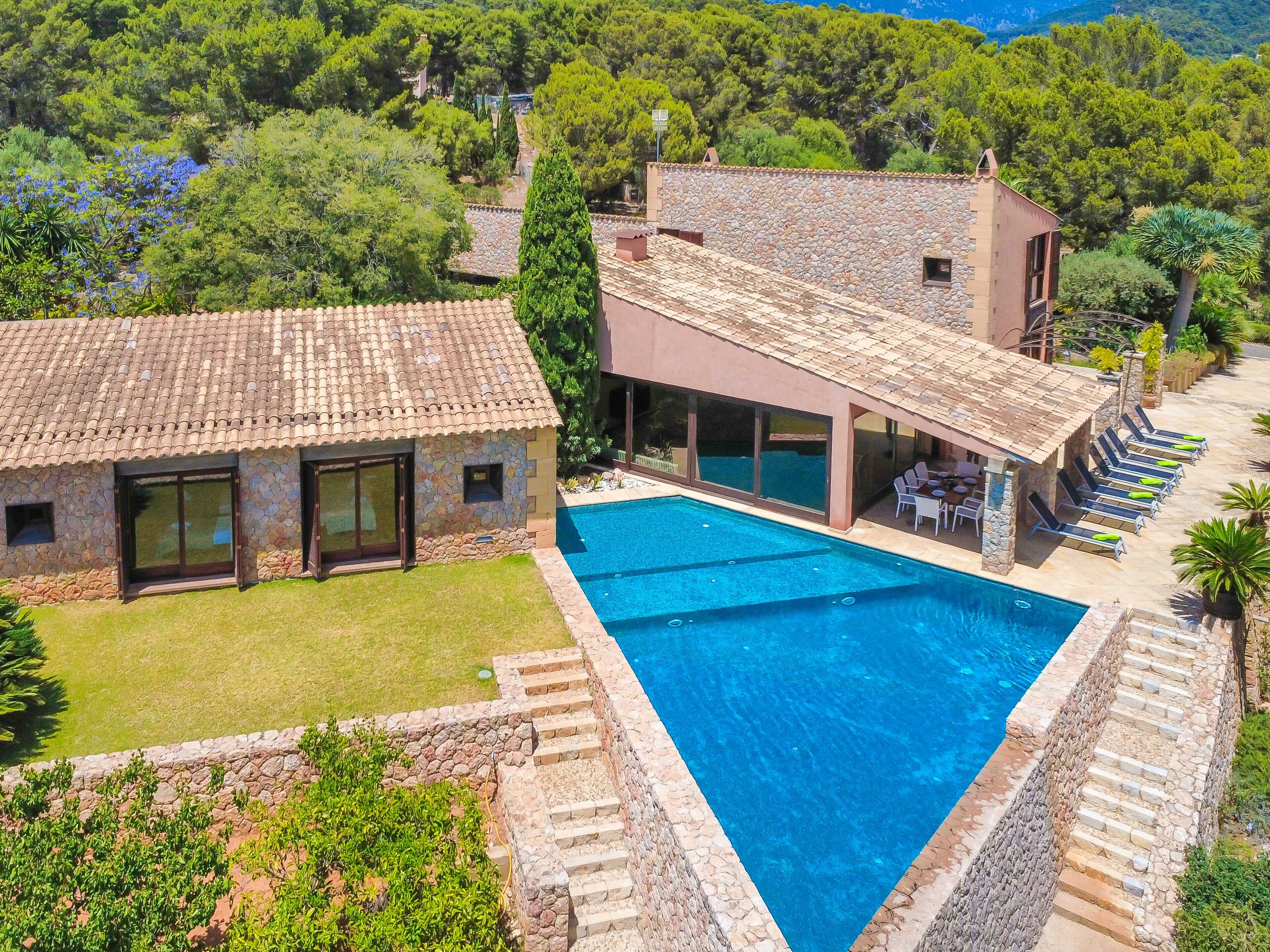 Eine Villa mit Swimmingpool, Steinmauern und einem Garten.