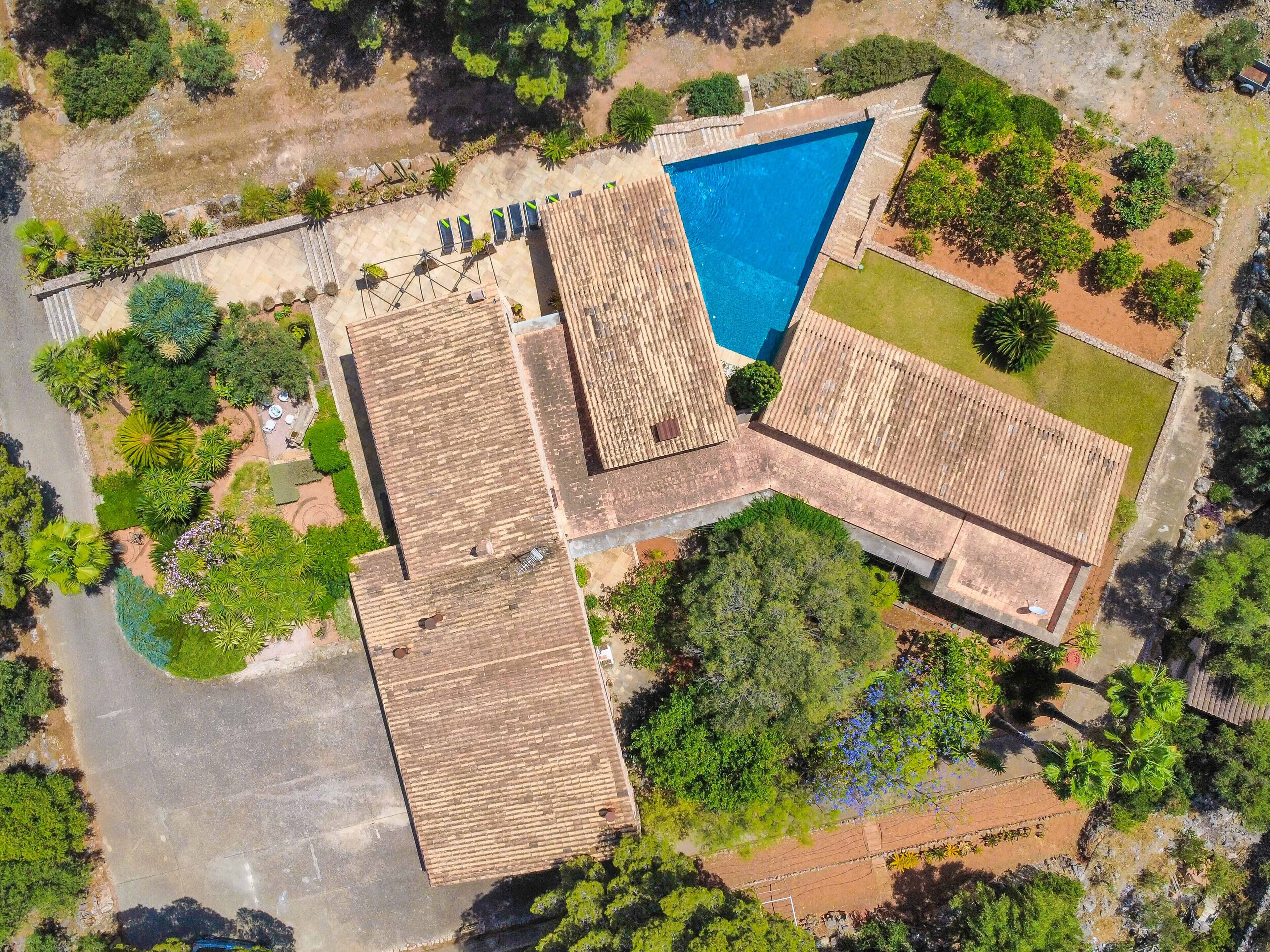 An aerial view of a property with a swimming pool, multiple buildings, and surrounding greenery.