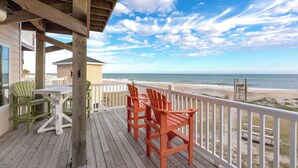 A wooden deck with chairs overlooking a beach.