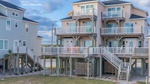 A beachfront property with multiple levels, wooden deck structures, and a staircase leading to the beach. - Crab House - Oceanfront 5 BR Home with Hot Tub & Community Pool (North Topsail Beach)