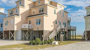 A multi-story building with a flat roof, wooden deck, and a staircase leading to the upper levels.