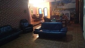 Sala de estar com parede de tijolos, um sofá azul, área de jantar com cadeiras e um quadro na parede.