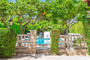 Zona de piscina con vistas a la piscina, rodeada de árboles y una valla decorativa.