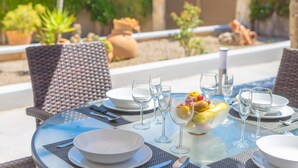 A round glass table set for dining with white plates, clear glasses, and a bowl of fruit. - CAN MIQUEL (TORD) - Fantastic house with terrace and private pool, and located just 300 me (Muro)