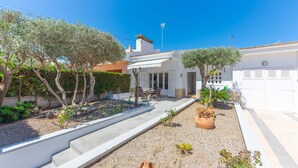 A white building with a covered patio, steps leading to the entrance, and a garden with potted plants and trees. - CAN MIQUEL (TORD) - Fantastic house with terrace and private pool, and located just 300 me (Muro)