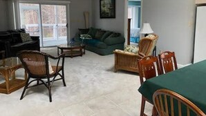 Una sala de estar con un sofá, sillas, una mesa de comedor y un ventilador de techo.