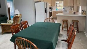 Una cocina con comedor, que incluye una mesa con sillas, un refrigerador y una ventana.