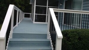 Una escalera que lleva a una casa con porche cubierto y ventanas amplias.