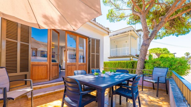 An outdoor patio with a table and chairs, a wooden door, and a large tree. - PDM CA'N NOFRE - Fantastic cosy house with terrace and with a the beach just 230 metres aw (Muro)