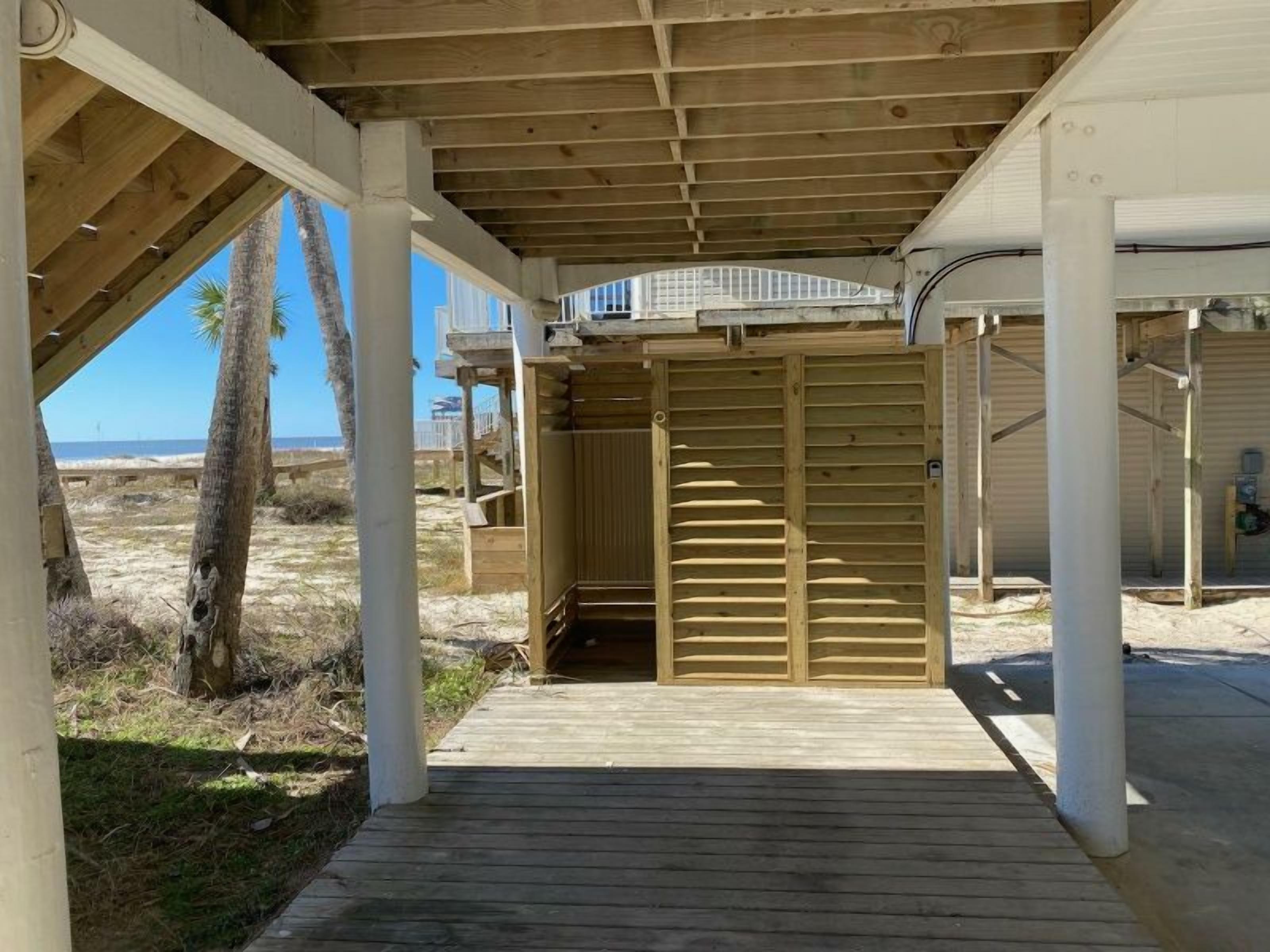 Un espacio al aire libre techado con una terraza de madera, una zona de estar protegida y vista a la playa.