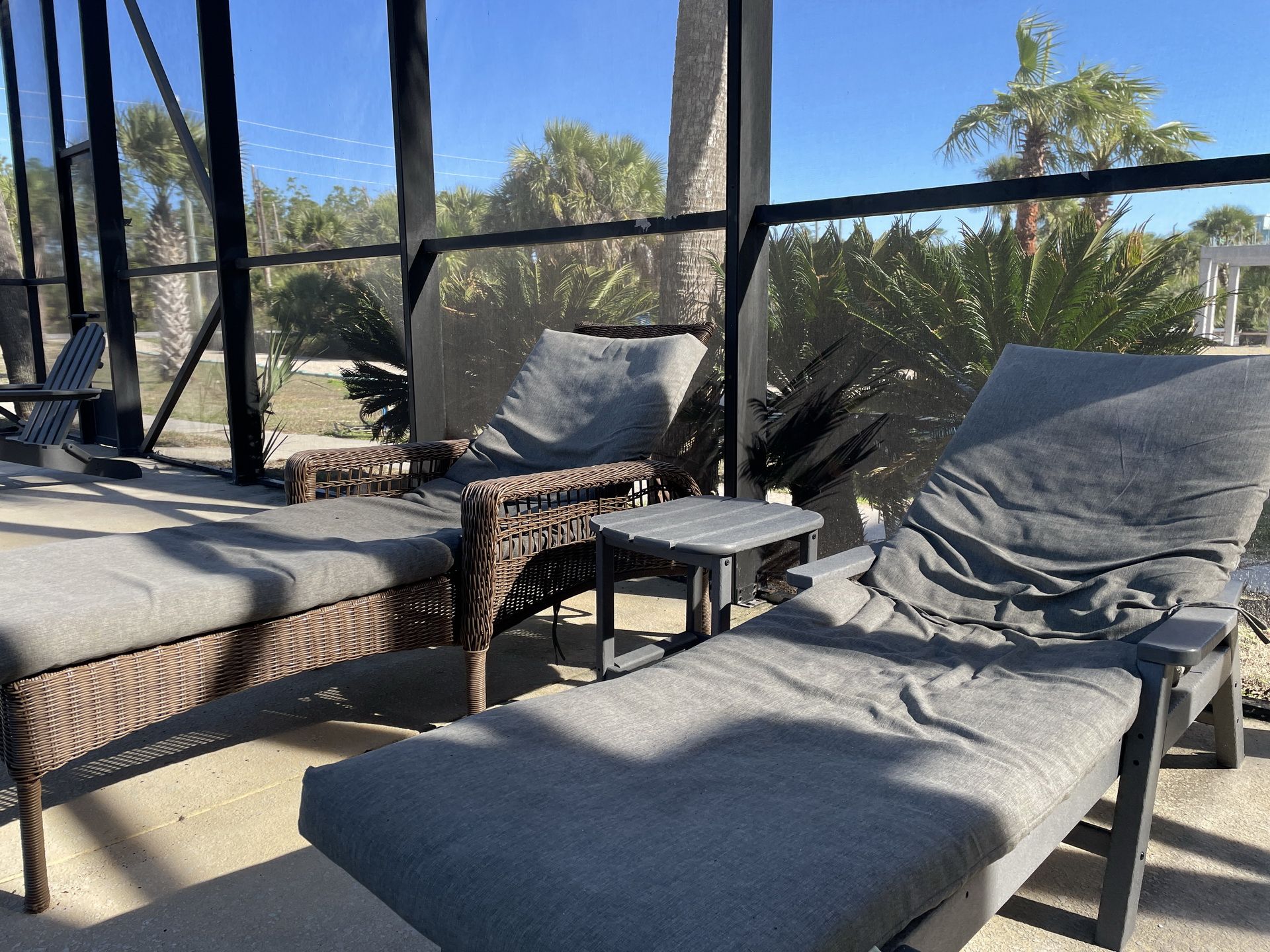 A covered outdoor seating area with wicker furniture and grey cushions.