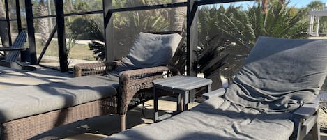 A covered outdoor seating area with wicker furniture and grey cushions.