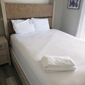 Una cama bien hecha con sábanas blancas y una toalla doblada al lado.