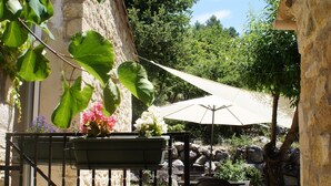 Een terras met een tafel, stoelen, een grote parasol en een stenen muur.