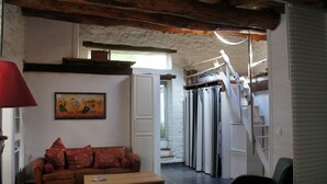 Een gezellige woonkamer met een houten plafond, een bruine bank, een houten salontafel en een rode lamp.
