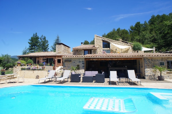 Un área junto a la piscina con sillones de descanso y piscina.