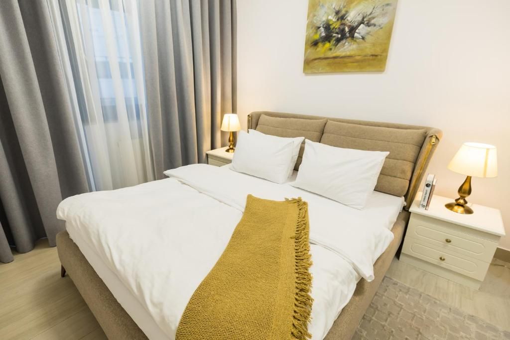 A hotel room with a bed, two bedside tables, a lamp, and a painting on the wall.