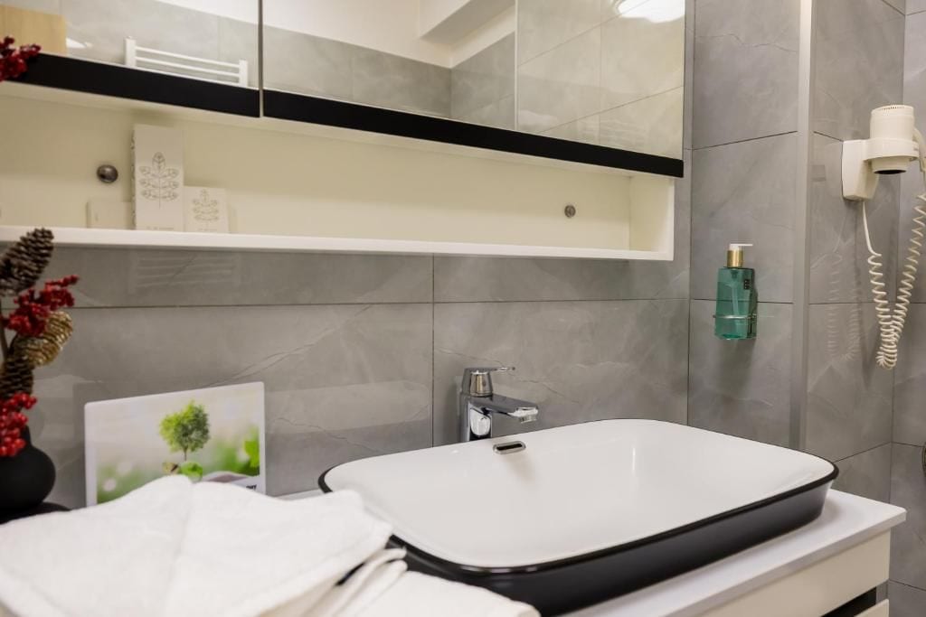 A modern bathroom with a white sink, a towel rack, and a mirror.