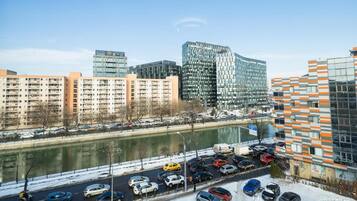 A cityscape with modern buildings, a river, and a parking lot with cars.